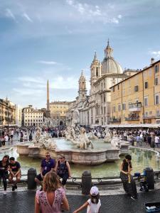 a group of people sitting around a fountain in a city at Navona Apartment in Rome