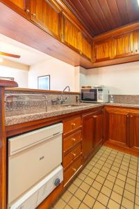 格拉玛多Completo 2 Suítes no Wish Resort no Centro的配有木制橱柜和水槽的厨房