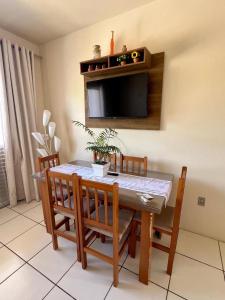 ein Esszimmer mit Tisch und Stühlen und einem Fernseher in der Unterkunft Lindo Apto Frente Praia 4 Cond Dom Felippe in São Lourenço do Sul + 14 Fotos