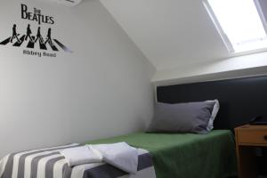 a small bedroom with a bed with a green blanket at Guest House Porto Clerigus in Porto