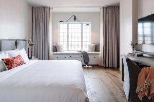 a bedroom with a large white bed and a window at The Alida, Savannah, a Tribute Portfolio Hotel in Savannah