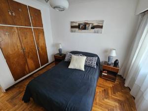 ein Schlafzimmer mit einem Bett mit einer schwarzen Decke und Holzböden in der Unterkunft Centro de Mar del Plata in Mar del Plata