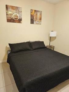 a bedroom with a black bed with two pictures on the wall at Heights at Mcoll Luxury Condo #2 in McAllen