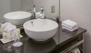 
a white sink sitting under a mirror in a bathroom at Hôtel Le Cantlie Suites in Montreal
