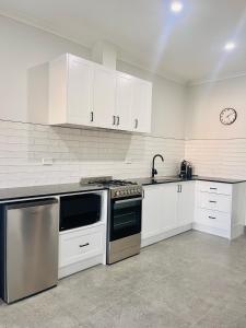 a kitchen with white cabinets and a stove at Cooper's Cottages in Lightning Ridge