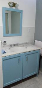 Un baño con un lavabo azul y un espejo. en Departamento calido, cerc, en Río Tercero