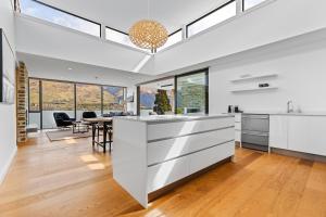 a kitchen with white cabinets and a dining room with a table at Penthouse with Marina Views - Studio or Two Bedroom Apartment in Wanaka