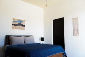 a bedroom with a blue bed and white walls at Desert Wind in La Ventana