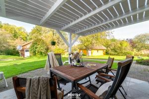 un tavolo e sedie in legno sotto un pergolato bianco di Ferienwohng Zum Garten Delve a Delve