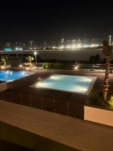 a swimming pool at night with a view of the ocean at The Perfect Couples Nest in Dubai