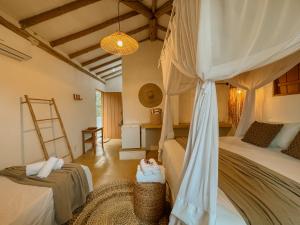 a bedroom with a canopy bed and a ladder at Villa Prana Caraíva in Caraíva