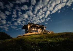 a house on top of a grassy hill at night at Atatū PurePod in Tormore