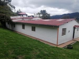 a white building with a red roof on a field at La pradera in Subachoque