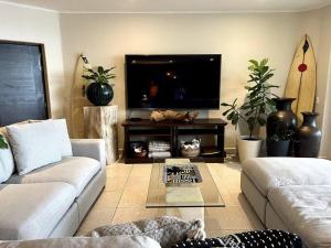 a living room with two couches and a flat screen tv at BEACH GETAWAY! Luxury Beachfront Condo in Punta de Mita! in Punta Mita