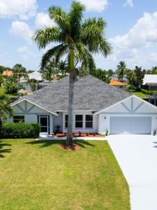 a palm tree in front of a white house at Endless Summer Hideaway w Pool ocean access 5br in Cape Coral