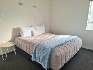 a bedroom with a large bed with a blue blanket on it at Ohope Beach Motel in Ohope Beach