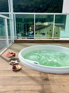 bañera grande en el balcón con algo de comida en Cobertura Santorini Nova com Spa e Solário na Praia Grande, en Ubatuba