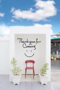 a red chair sitting under a sign that reads thank you for coming at The Star Pool Villa Hatyai in Hat Yai