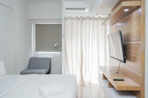 une chambre avec un lit, une télévision et une chaise dans l'établissement Relax and Simply Studio Apartment at Parkland Avenue By Travelio, à Tangerang