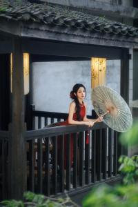 a woman standing on a railing holding an umbrella at QingXi Hotel in Fenghuang