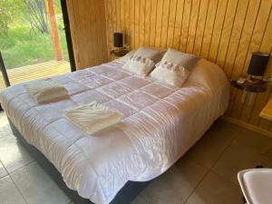 a bed with white sheets and pillows in a bedroom at Raíces del Ñuble in San Fabián de Alico