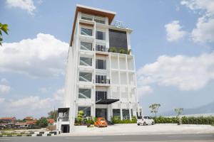 a tall white building with cars parked in front of it at Toyo Hotel Purwokerto, Azana Hotels Collection in Banyumas