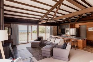 ein Wohnzimmer mit einem Sofa und Stühlen sowie eine Küche in der Unterkunft Waterfront Boltons Beach Cottages in Little Swanport