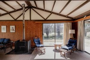 ein Wohnzimmer mit blauen Stühlen und einem Kamin in der Unterkunft Waterfront Boltons Beach Cottages in Little Swanport