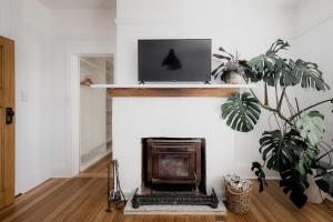 a living room with a fireplace with a tv on the wall at House on The Hill in Hobart