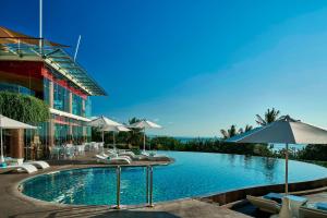 a swimming pool with chairs and umbrellas next to a building at Sheraton Bali Kuta Resort in Kuta
