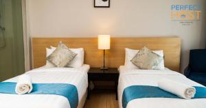 a hotel room with two beds and a table with a lamp at The Straits Melaka by Perfect Host in Malacca