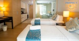 a hotel room with two beds and a desk at The Straits Melaka by Perfect Host in Malacca