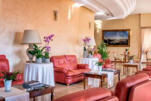 poczekalnia z czerwonymi krzesłami i stołami w obiekcie Astura Palace Hotel w mieście Nettuno