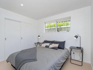 a white bedroom with a bed and a window at Greenhills Charmer - Coromandel Town Holiday Home in Coromandel Town