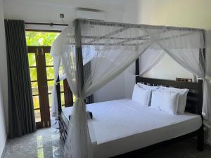 a bedroom with a canopy bed with white pillows at Birds Nest 2 in Bandaramulla