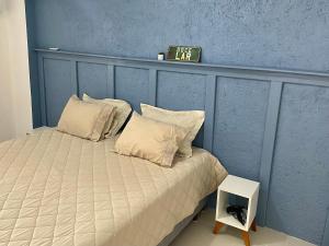 a bed with two pillows and a clock on the wall at Loft Aconchegante Apartamento Floripa 12 - Wi-fi 600Mb in Florianópolis