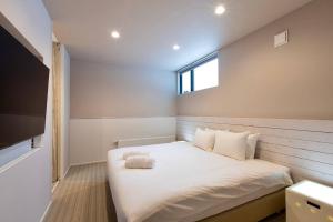 a bedroom with a large white bed with a window at Olaf House in Niseko