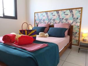 a bedroom with a bed with blue and pink pillows at charmante maison in Les Avirons