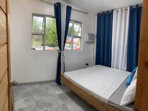 a bedroom with a bed with blue curtains and a window at Kidapawan Staycation 1 in Manongol