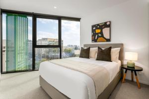 a bedroom with a large white bed and large windows at Kangaroo Point Apartment by Urban Rest in Brisbane