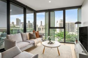 a living room with a couch and a large window at Kangaroo Point Apartment by Urban Rest in Brisbane