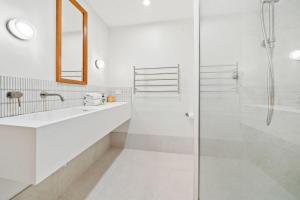 a white bathroom with a shower and a sink at Claytons 7 by Discover Stradbroke in Point Lookout +19 photos