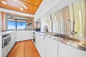 a large kitchen with white cabinets and a window at Claytons 7 by Discover Stradbroke in Point Lookout