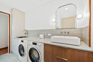 a bathroom with a sink and a washing machine at Claytons 7 by Discover Stradbroke in Point Lookout