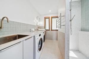 a white laundry room with a sink and a washing machine at Claytons 7 by Discover Stradbroke in Point Lookout