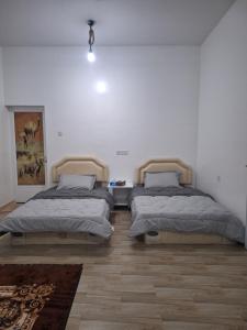two beds in a white room with a rug at Al Falak Chalet in Al Raka