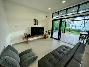a living room with a couch and a flat screen tv at Villa Pandan Simeulue in Salul
