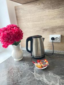 a vase of pink flowers and a coffee pot and a vase of roses at Самрук Towers,жилой комплекс in Taldykolʼ