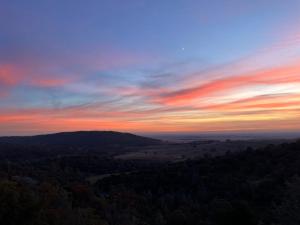 a sunset from the top of a hill with trees at Breathtaking view of the Hills with HotTub, Pool and Pool Table in Marble Mountain