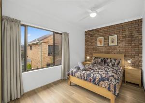 a bedroom with a bed and a large window at Banksia in Sawtell